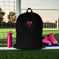 Black soccer mom backpack with pink logo on grass in front of a soccer goal