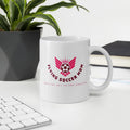 White mug with 'Flying Soccer Mom' design on a desk with a plant and books in the background