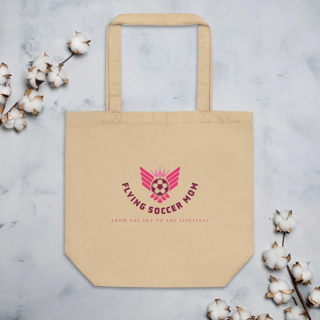 Soccer mom holding a soccer mom tote bag with a logo on a soccer field