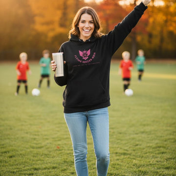 Soccer mom in black hoodie with logo on a soccer field with children playing in the background