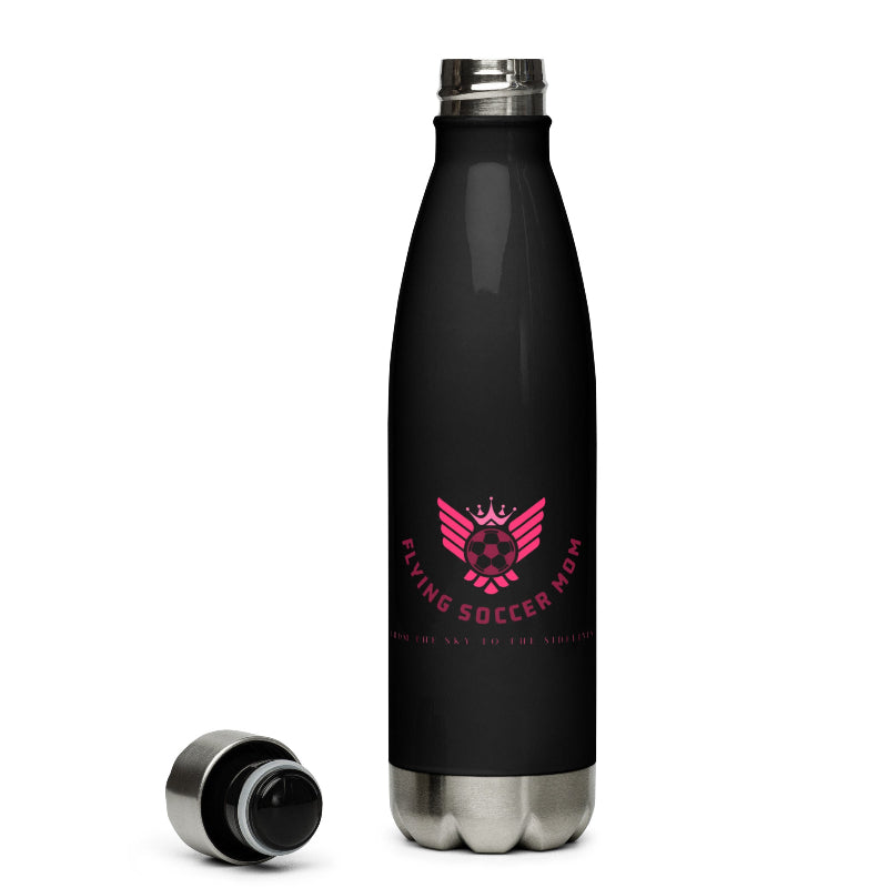 Black soccer mom water bottle with pink logo on a soccer field with shoes and a towel.