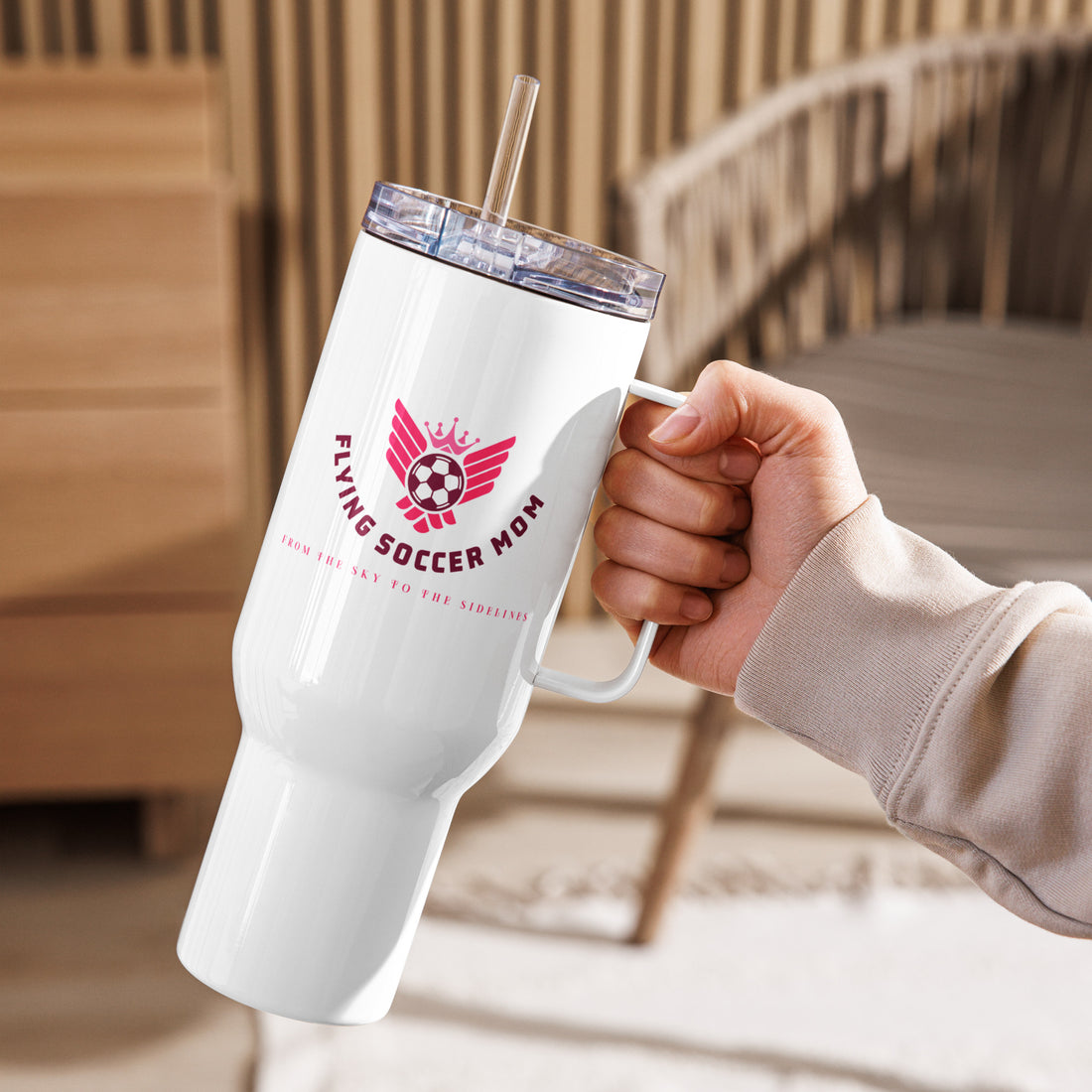 Hand holding a Flying Soccer Mom stainless steel tumbler with handle, perfect for busy mornings and game days.